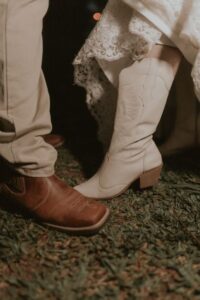 A group of people dancing in western attire with cowboy boots on a wooden dance floor.