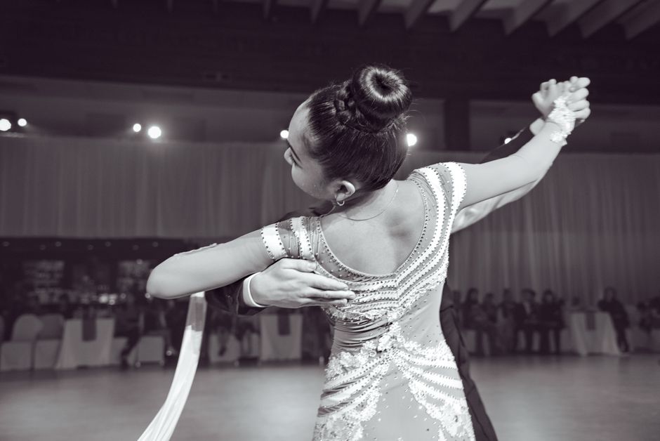Couples and individuals in casual attire dancing together on a well-lit wooden dance floor.